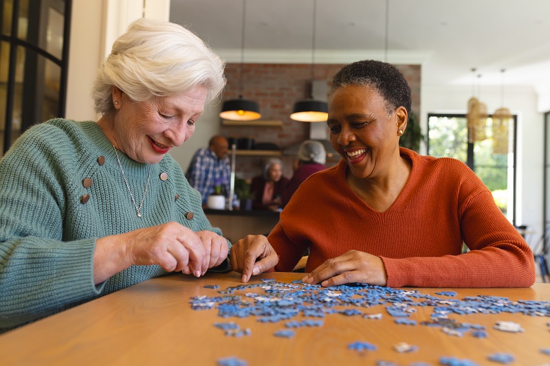5 Best Brain Games for Seniors to Improve Memory: A PT’s Cognitive Health Guide happy diverse senior female friends playing with jigsaw puzzles in sunny dining room at home
